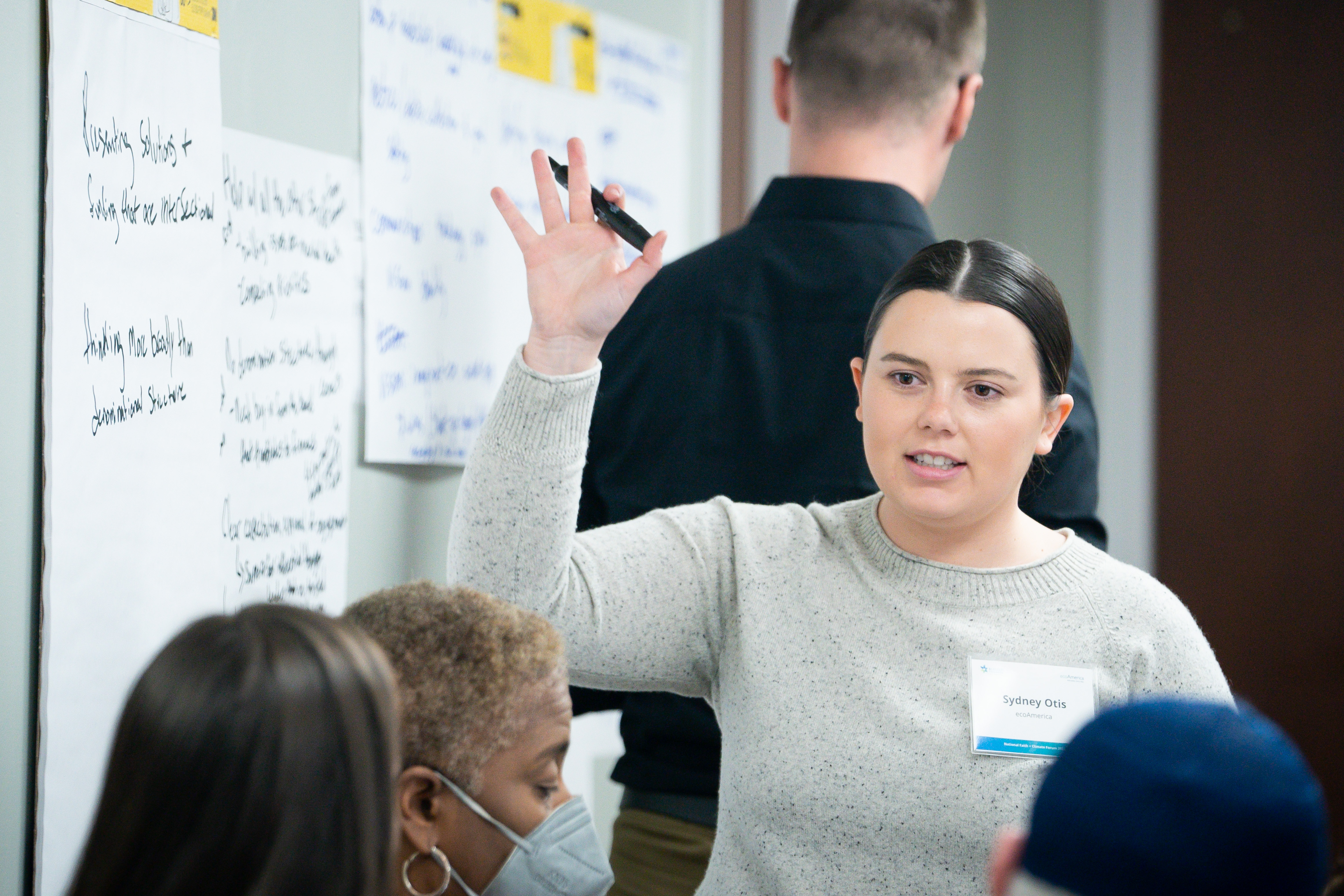 A woman confidently presenting to a group of attentive individuals.